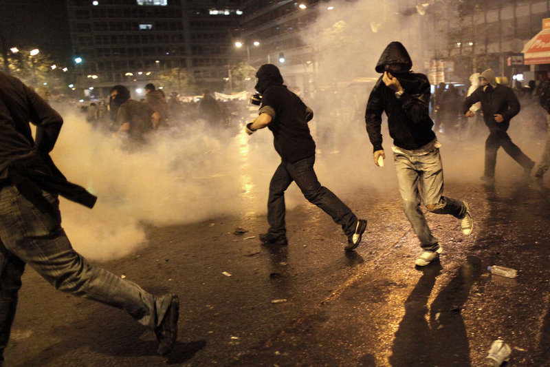 Rioting youths clash with police dispensing tear gas near the Greek parliament Wednesday when the nation’s fragile coalition government approved of budget cuts that, among other things, will lead to tax increases as well as further reductions in pensions and salaries.