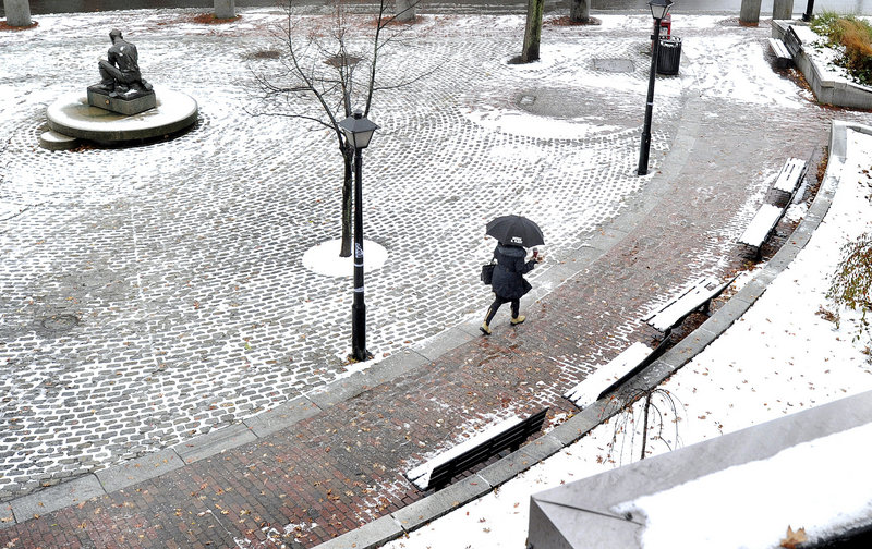 As the first snowfall of the season turns to rain, a pedestrian on Temple Street in Portland uses an umbrella. Most places saw just a few inches of snow before the rains came.