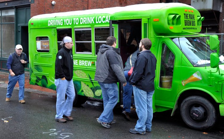 Zach Poole, right, greets tour members as they board the Maine Brew Bus behind the Thirsty Pig for a  2014 tour of two breweries, a meadery, a coffee roaster, a fermenter and distiller over several hours.
