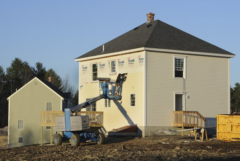 A worker installs siding Friday on a new home in the Sunrise Ridge subdivision along the Portland Road in Buxton. In southern Maine, places where construction of new homes has increased substantially since last year include Kittery, Waterboro and Wells.