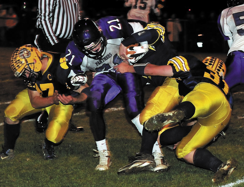 Racean Wood of Waterville looks for room to run Friday night as three Mt. Blue players converge on the tackle during the Eastern Class B championship game at Farmington. Undefeated Mt. Blue won, 42-14.