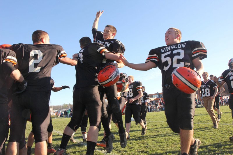 Winslow quarterback Matthew Fortier jumps into the arms of T.J. Mitchell, while Joe Hopkins, left, and Bryce Gilliland join the victory celebration.
