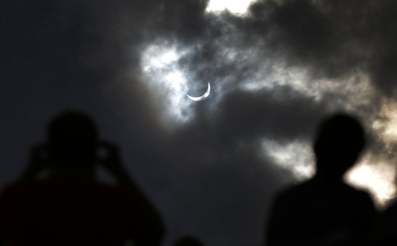 Tourists watch as the moon blocks the sun Wednesday in Cairns, northern Australian. Totality – the darkness at the eclipse’s peak – lasted just over two minutes.