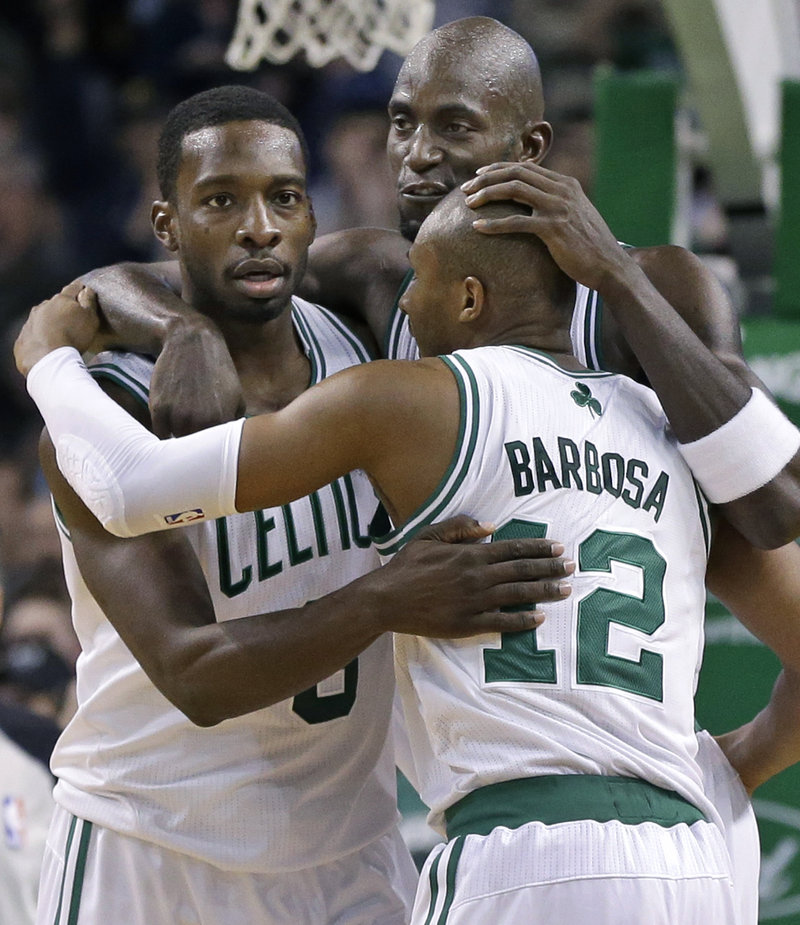 Reserves Jeff Green, left, and Leandro Barbosa are hugged Wednesday night by Kevin Garnett after helping the Boston Celtics beat the Utah Jazz, 98-93.