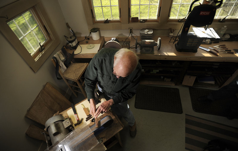 Bruce Bohrmann fashions the handle of a knife in his Yarmouth workshop earlier this month. “I can start working on a blade and I can tell immediately if it’s going to love me or hate me,” Bohrmann said. “The steel talks to me, and I swear back at it.”