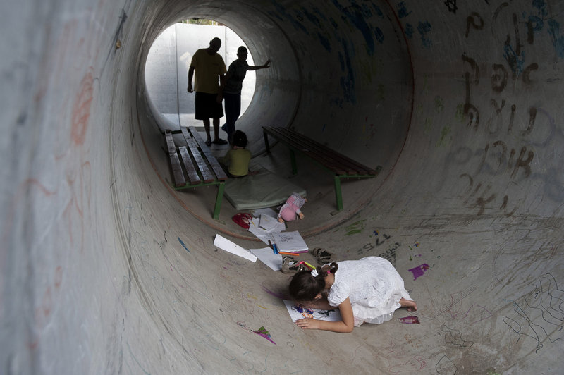 Israelis hide in a concrete tube during a rocket attack from Gaza, in Nitzan, southern Israel, on Monday.