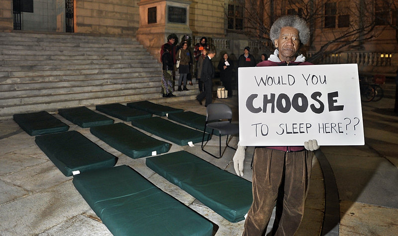 Nick Nicholson with Homeless Voices for Justice stands near pads homeless people sleep on in shelters during a vigil Monday at Portland City Hall.