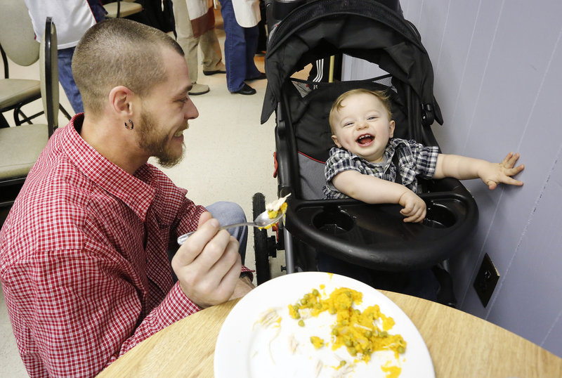 Jeremy Cormier of Auburn feeds his 14-month-old son, Ashton, on Thursday during the 17th annual Thanksgiving dinner. VFW Post 832 in South Portland was decked out like a restaurant for the event, with volunteers serving the guests.