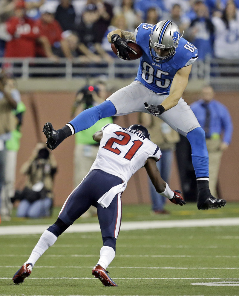 Tony Scheffler of the Detroit Lions leaps over Houston defensive back Brice McCain during overtime Thursday. The Texans improved to 10-1 with a 34-31 victory.