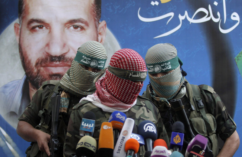 Hamas militants talk during a press conference in Gaza City on Thursday. The poster reads: “Gaza won” and shows Ahmed Jabari, the Hamas leader assassinated on Nov. 14, which set off the last round of fighting.