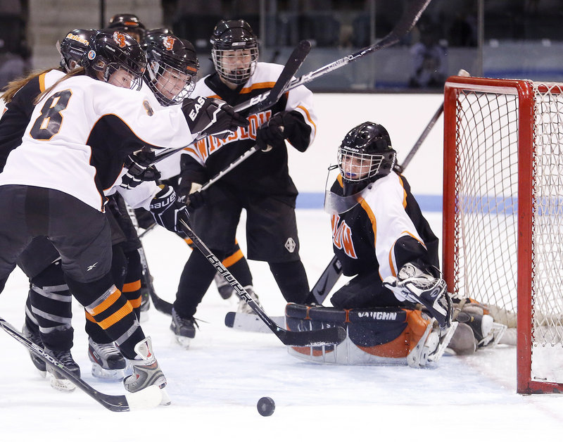 Photos by Derek Davis/Staff Photographer Jessica Cain, whose goaltending kept Winslow in the game Friday night, keeps her eye on the puck as Grace Rabinowitz, left, and Rachel Maroney of Brunswick swoop in for a rebound. Cain made 32 saves in a 4-3 victory to open the season. Brunswick held a 49-23 advantage in shots.