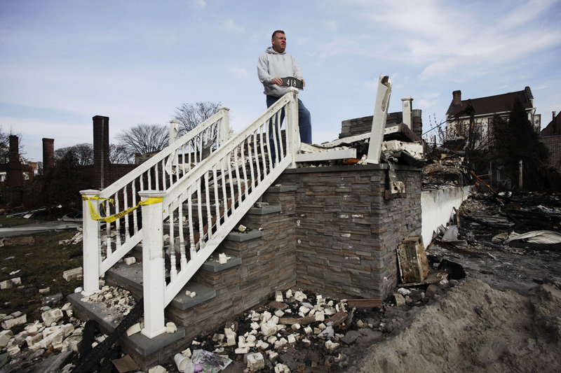 Ray Marten poses by his destroyed home in Queens, N.Y., which burned when Sandy hit the area. Rebuilding is expected to provide the region a huge economic boost.