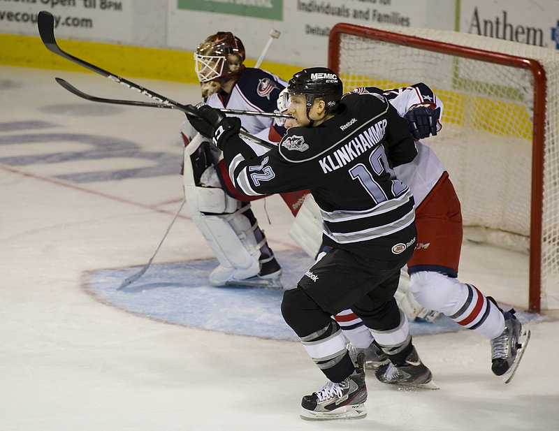 Rob Klinkhammer of the Portland Pirates attempts to gain position in front of the Springfield net while being checked by Theo Ruth of the Falcons. The goalie is Curtis McElhinney.