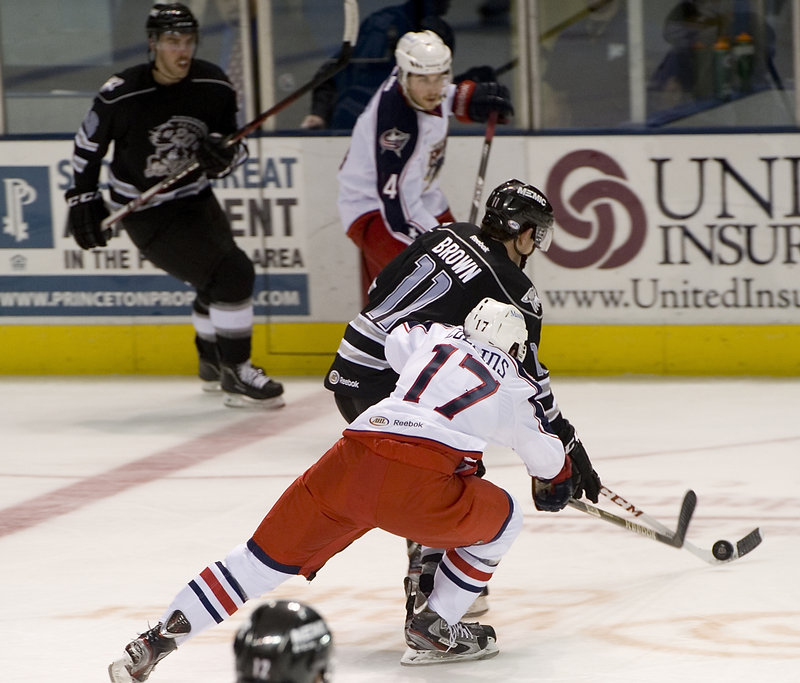 Chris Brown of the Portland Pirates knocks the puck into the Springfield zone past Sean Collins of the Falcons.