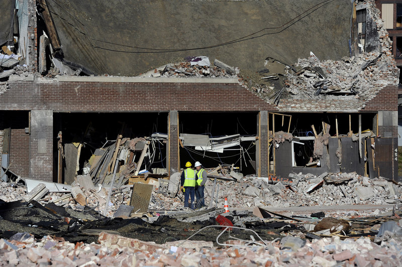 Inspectors stand in debris Saturday at the site of a gas explosion that damaged dozens of buildings and injured 18 people in Springfield, Mass., on Friday evening.