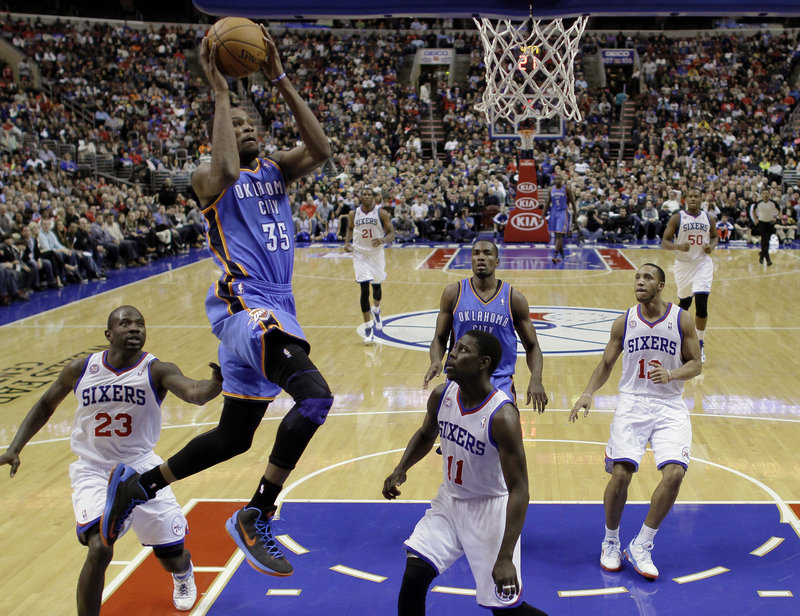 Kevin Durant of the Oklahoma City Thunder breezes by the Philadelphia 76er defenders in the first half Saturday night. Durant scored 37 points in a 116-109 overtime victory.