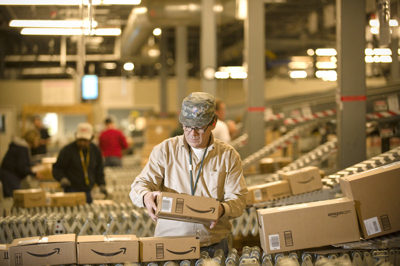 An Amazon.com employee grabs boxes off the conveyor belt to load in a truck at its Fernley, Nev., warehouse. Shoppers were expected to spend 20 percent more this Cyber Monday than the same day last year.