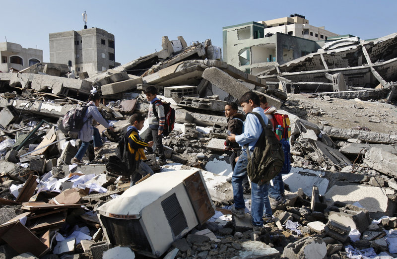 Palestinian schoolchildren walk Monday in the rubble of the Hamas interior ministry in Gaza City, which was flattened previously by Israeli bombs during eight days of airstrikes.