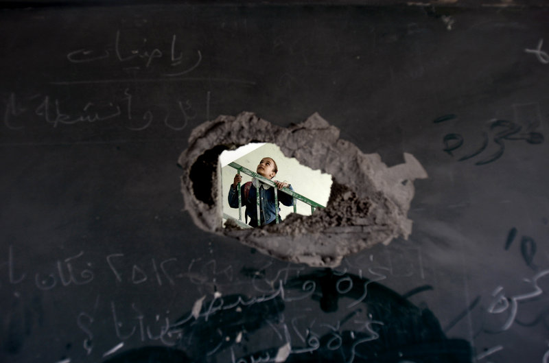 A Palestinian schoolgirl is seen through a hole in a blackboard Monday, days after an Israeli strike hit a school in Gaza City. Readers differ on how to reach resolution to the Israeli-Arab conflict.