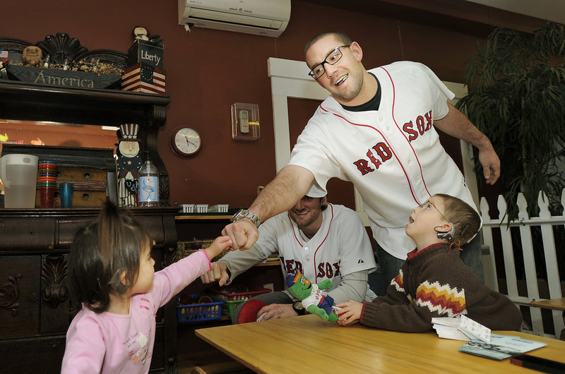 Natalie Morin gives fist bumps to pitcher Chris Carpenter and outfielder Ryan Kalish while her brother Thomas looks on at the Briarwood Children’s House in Lyman Tuesday morning.