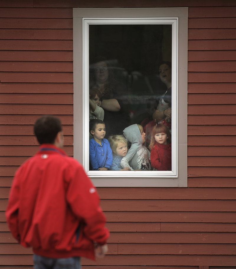 Children at Briarwood Children’s House gather by a window waiting for Wally the Green Monster and his baseball buddies late Tuesday morning.