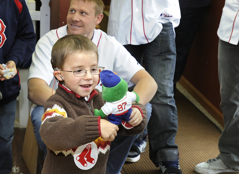 Thomas Morin stares in fascination at his new Wally the Green Monster while Sox pitcher Mark Melancon watches from behind.
