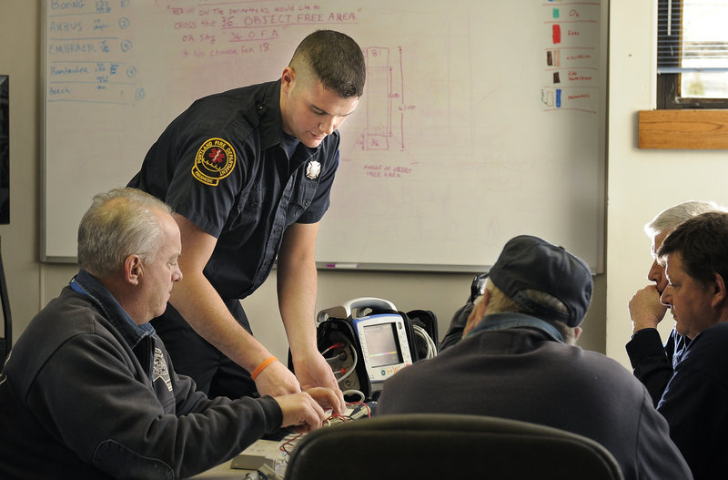 Ryan Walsh of the Portland Fire Department shows Jetport firefighters Tuesday how to work the new Zoll X-Series frontline monitors that the city will carry in its MEDCU units. The devices monitor the frequency and depth of compressions as CPR is being administered.