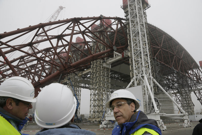 Workers assist Tuesday in the raising of a gigantic steel arch to cover remnants of the exploded reactor at the Chernobyl nuclear power plant. The new safe confinement will cover a hastily built sarcophagus erected shortly after the world’s worst nuclear accident in 1986.