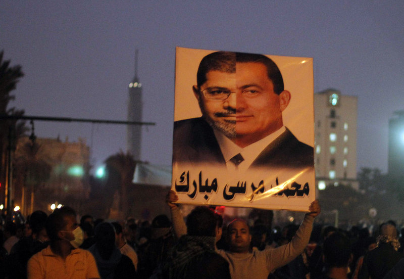A protester holds up a poster with the faces of former Egyptian President Hosni Mubarak and current President Mohmmed Morsi combined.