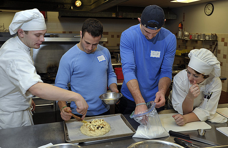 Culinary arts students Dillon Newcombe. left, and Audrey Carlson help Andy Miele and Chris Brown put an egg mixture glaze on the crust for a rustic apple tart they are making Tuesday. Brown said he hopes the cooking class helps him eat more healthy meals.