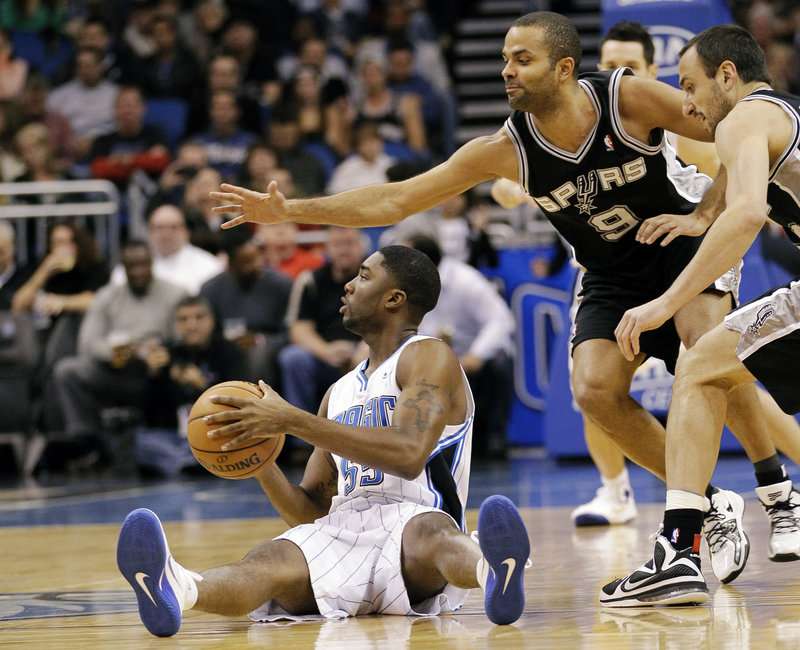 E’Twaun Moore of the Orlando Magic looks to pass Wednesday night after beating Tony Parker, 9, and Manu Ginobili of San Antonio to a loose ball. The Spurs won, 110-89.