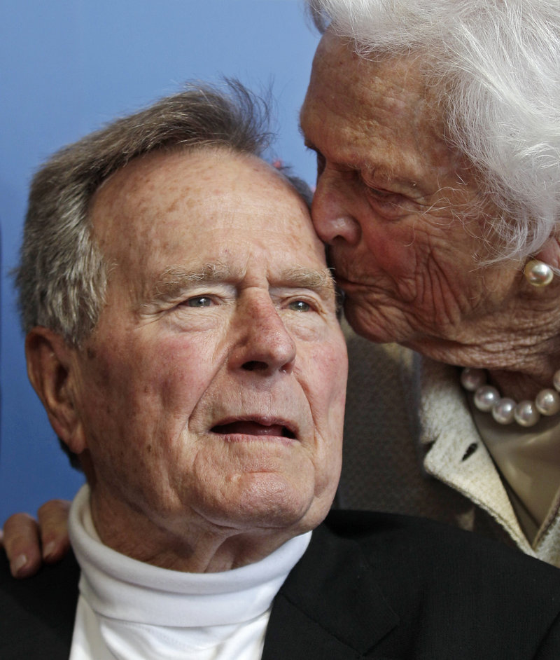 Former President George H.W. Bush gets a kiss from the former first lady. Doctors say they want to keep him hospitalized until the cough goes away.