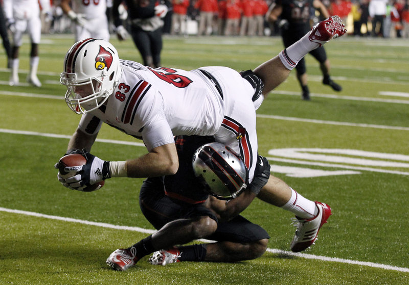 Ryan Hubbell, Louisville tight end, lunges over a Rutgers defender during first-half action of Thursday night’s game in Piscataway, N.J., won by the Cardinals.