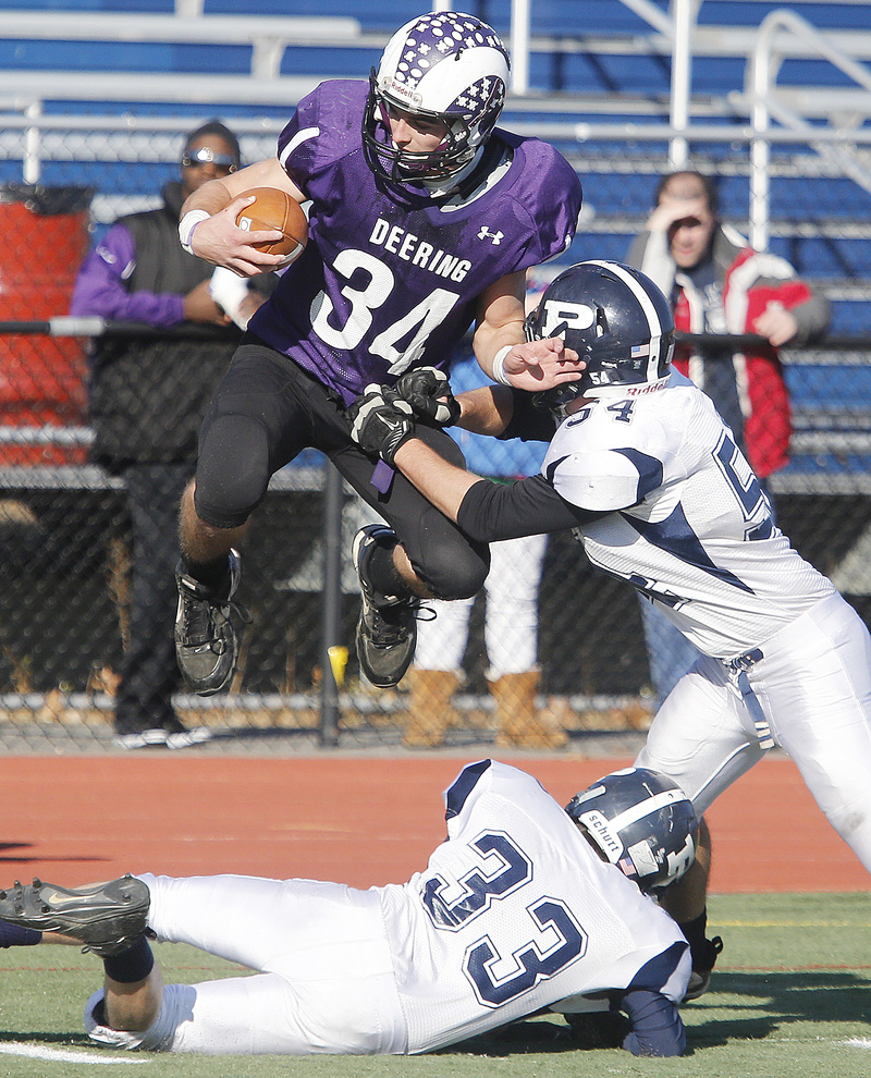 Kenny Sweet, who carried 22 times for 249 yards for Deering, is hit by Tate Gale of Portland, right, while trying to leap over Dominic Fagone of the Bulldogs. Deering won 28-14 in the annual Thanksgiving game.