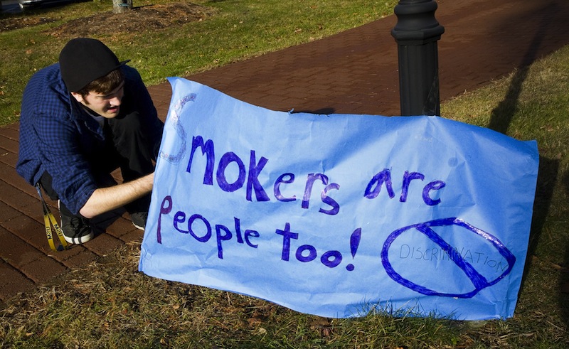 USM freshman Joshua Thornberg sets up a sign during a protest of a proposed smoking ban on USM campuses, at the Gorham campus on Monday.