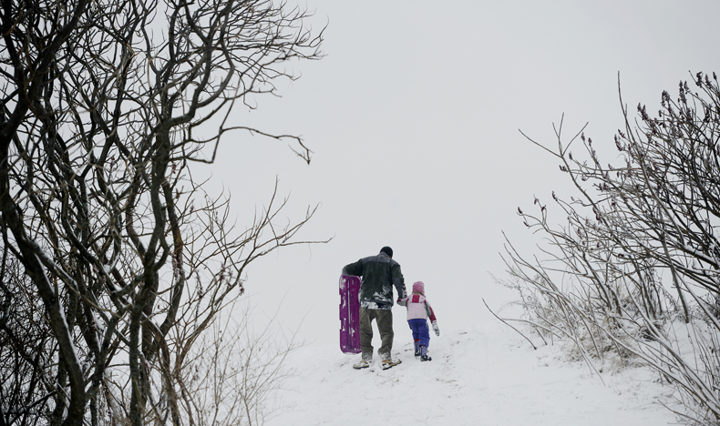 Ryan Guite of South Portland walks up the hill on the Eastern Prom in Portland with his daughter Emma, 4, after a trip down the hill on a sled Monday.