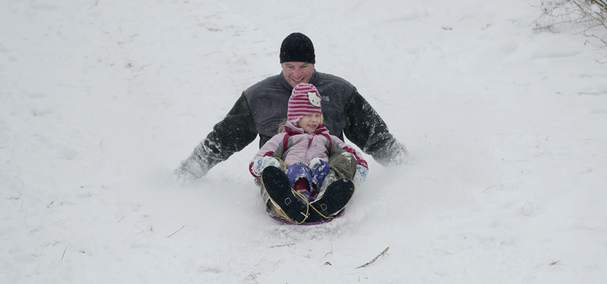 Ryan Guite of South Portland slides down the hill on Eastern Prom in Portland with his daughter Emma, 4, on Monday.