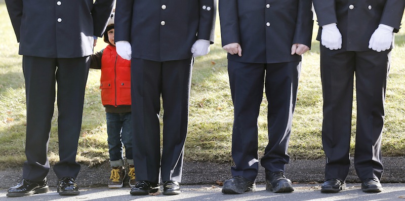 A child peers through firefighters standing as the procession heads to the cemetery outside the funeral for school shooting victim Daniel Gerard Barden at St. Rose of Lima Catholic Church in Newtown, Conn., on Wednesday. According to firefighters, Daniel wanted to be a firefighter when he grew up and they honored him at the service. Barden, 7, was killed when Adam Lanza walked into Sandy Hook Elementary School in Newtown, Conn., Dec. 14, and opened fire, killing 26 people, including 20 children, before killing himself.