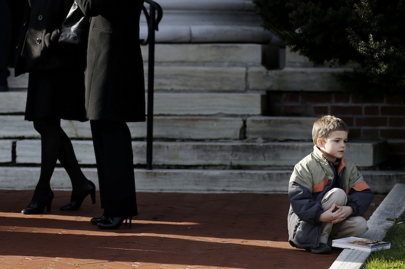 The Associated Press A boy sits outside a church before the memorial service for Lauren Rousseau in Danbury, Conn., on Thursday. Rousseau, 30, was one of the 26 teachers and children shot to death at Sandy Hook Elementary School last Friday.