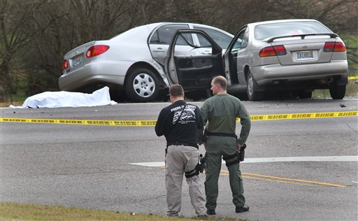 Authorities stand watch over a scene where a body lies covered with a sheet on Highway 78 in Oxford, Ala., on Saturday. Police officers in eastern Alabama shot an assailant armed with an AK-47 assault rifle toward the end of a pursuit that left several people injured, including Heflin police officer Jackie Stovall, authorities said.