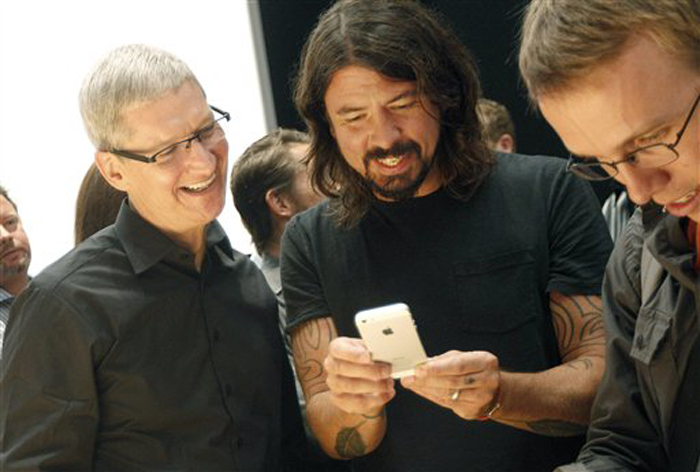 Apple CEO Tim Cook, left, talks with musician Dave Grohl of the Foo Fighters as they look at an iPhone 5 during an Apple event in San Francisco in September.