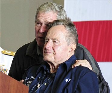 In this June 10, 2012 photo provided by the U.S. Navy, former Presidents George W. Bush, left, and his father, George H.W. Bush, deliver remarks to the crew during a ceremony aboard the aircraft carrier USS George H.W. Bush (CVN 77). Former President George H.W. Bush will spend Christmas in a Houston hospital after developing a fever and weakness following a monthlong, bronchitis-like cough. (AP Photo/U.S. Navy, Petty Officer 2nd Class Maria Rachel D. Melchor)