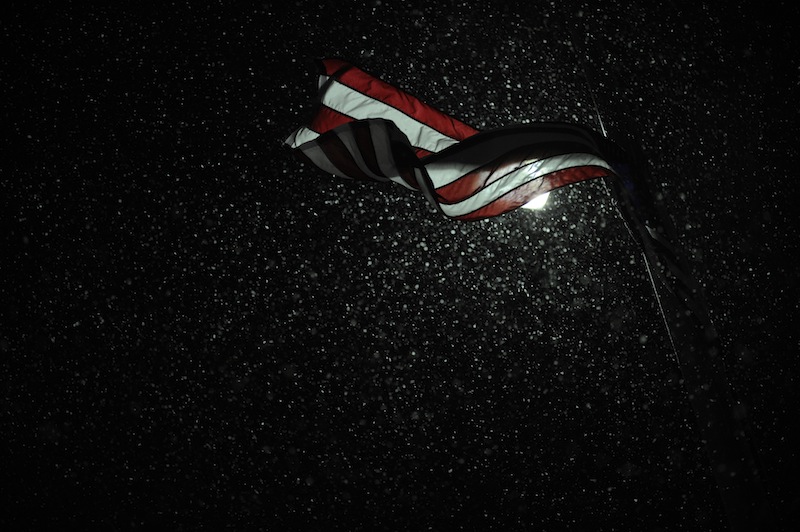 Snow is illuminated by a street light as an American flag blows in the wind during a winter storm Wednesday, Dec. 26, 2012, in Paducah, Ky. An enormous storm system that brought snow and sleet to the nation's midsection -- and tornadoes to the Deep South -- is now moving its way toward the Northeast. (AP Photo/Stephen Lance Dennee)
