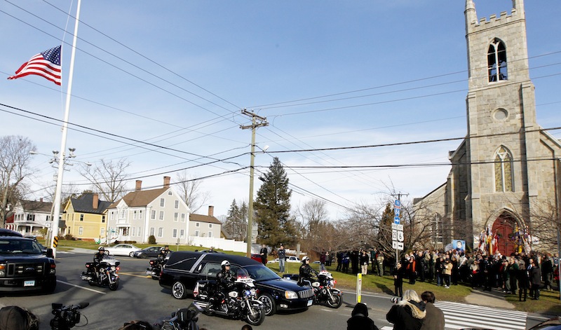 While mourners gather outside of Trinity Episcopal Church on Thursday during funeral services for Benjamin Andrew Wheeler, one of the students killed in the Sandy Hook Elementary School shooting last week, a hearse with another shooting victim passes by.
