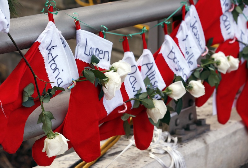 In this Wednesday, Dec. 19, 2012 file photo, Christmas stockings with the names of shooting victims hang from railing near a makeshift memorial near the town Christmas tree in the Sandy Hook village of Newtown, Conn. In the wake of the shooting, the grieving town is trying to find meaning in Christmas. (AP Photo/Julio Cortez, File)