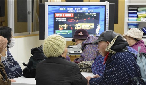 Tsunami evacuees watch TV news flashing a tsunami warning at their shelter at Takata Junior High School that stands on a higher ground in Rikuzentakata in Iwate Prefecture on Friday after a strong earthquake struck off the coast of northeastern Japan.