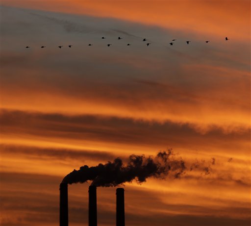 Geese fly past the smokestacks at the Jeffrey Energy Center coal power plant as the sun sets near Emmett, Kan.