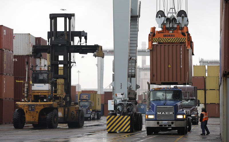 In this Dec. 18, 2012 file photo, a truck driver watches as a freight container, right, is lowered onto a tractor trailer by a container crane at the Port of Boston in Boston. The crane and a reach stacker, left, are operated by longshoremen at the port. The longshoremen's union may strike if they are unable to reach an agreement on their contract, which expires Dec. 29, 2012. A walkout by dock workers represented by the International Longshoremen’s Association would bring commerce to a near halt at ports from Boston to Houston. (AP Photo/Steven Senne, File)