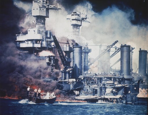 In this U.S. Navy file photo, a small boat rescues a USS West Virginia crew member from the water after the Japanese bombing of Pearl Harbor on Dec. 7, 1941. Two men can be seen on the superstructure, upper center. The mast of the USS Tennessee is beyond the burning West Virginia.
