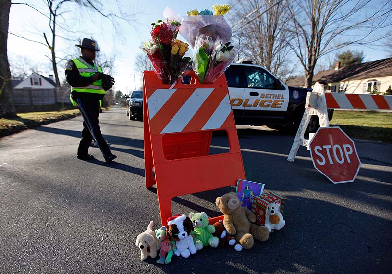 A police roadblock serves as a makeshift memorial at the corner of Riverside and Cherry Streets on Saturday in Newtown, Conn.
